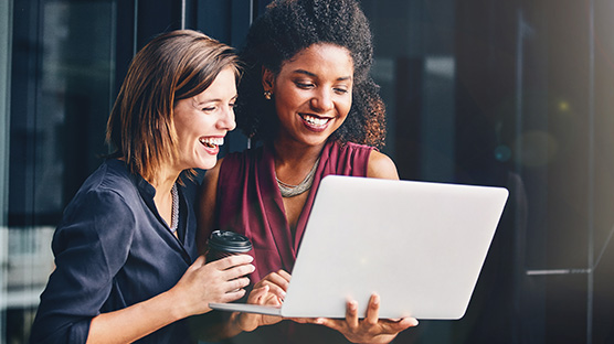 Foto zwei Frauen schauen sich etwas auf Laptop an