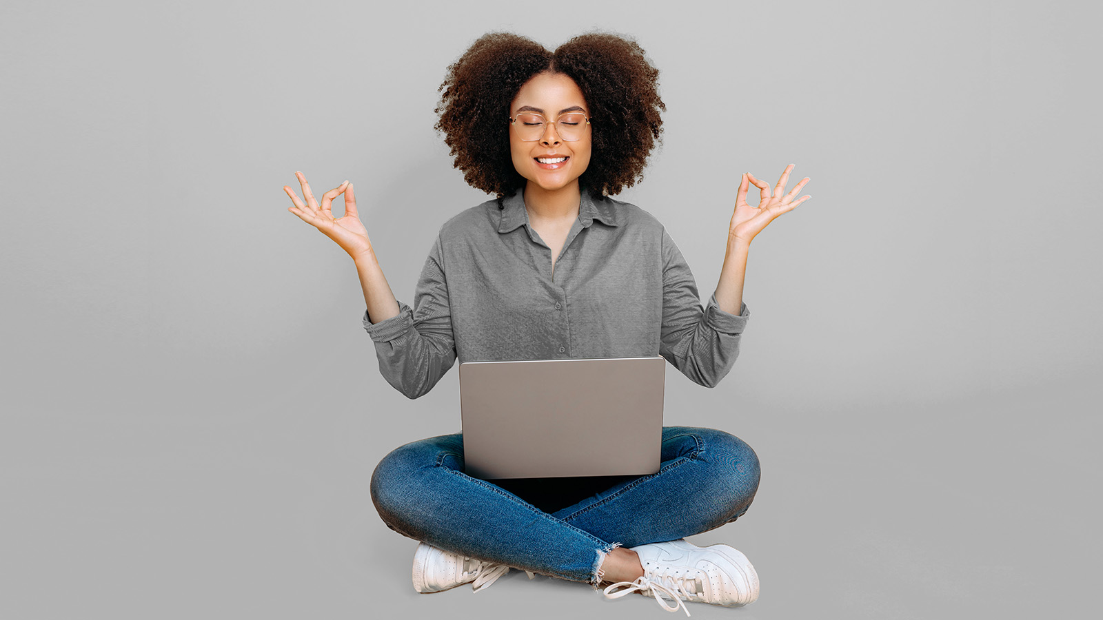person meditating with laptop