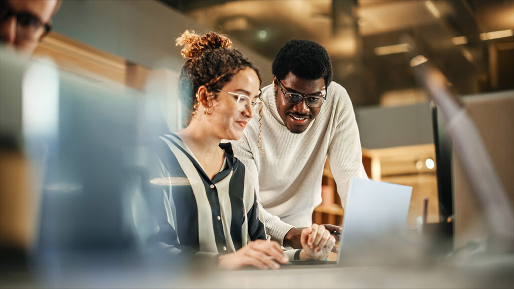 Two individuals at a laptop in discussion about Learning Management Systems