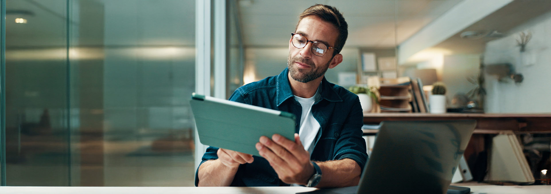 One person at his desk with a laptop, tapping on a tablet